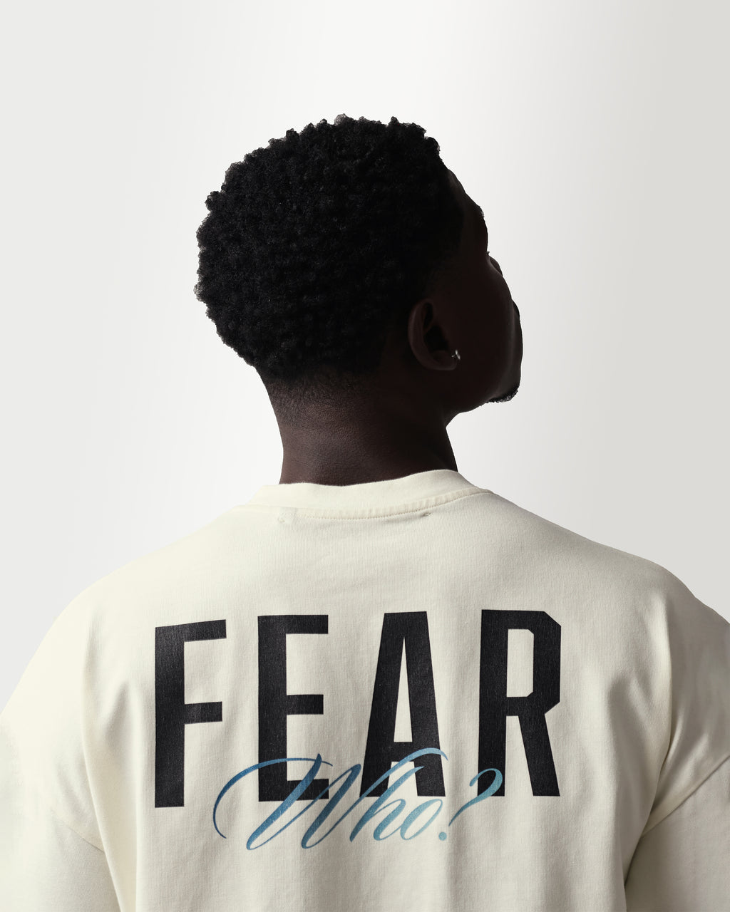 Person wearing a shirt with 'FEAR Who?' text on the back against a white background